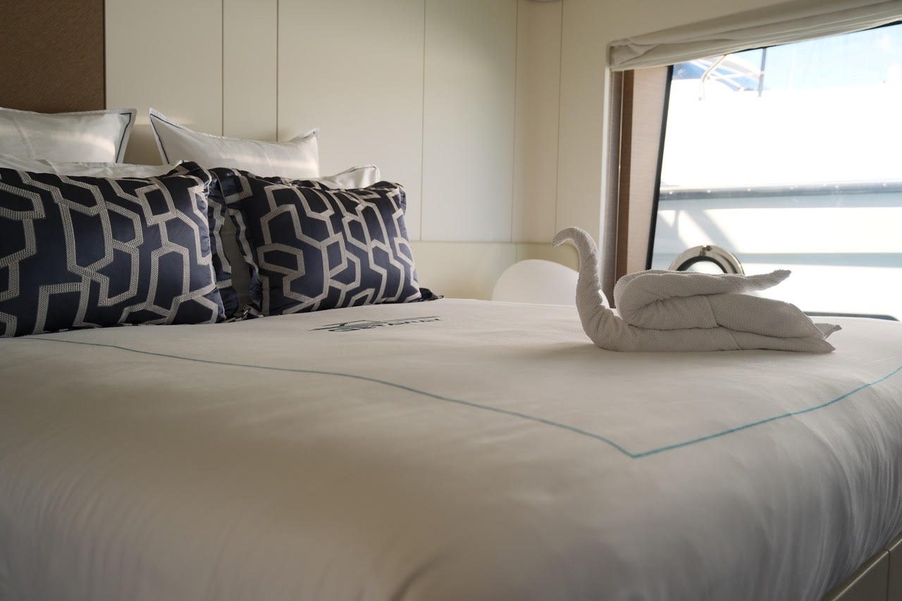 Made-up double bed in a guest cabin, with a towel swan by the window
