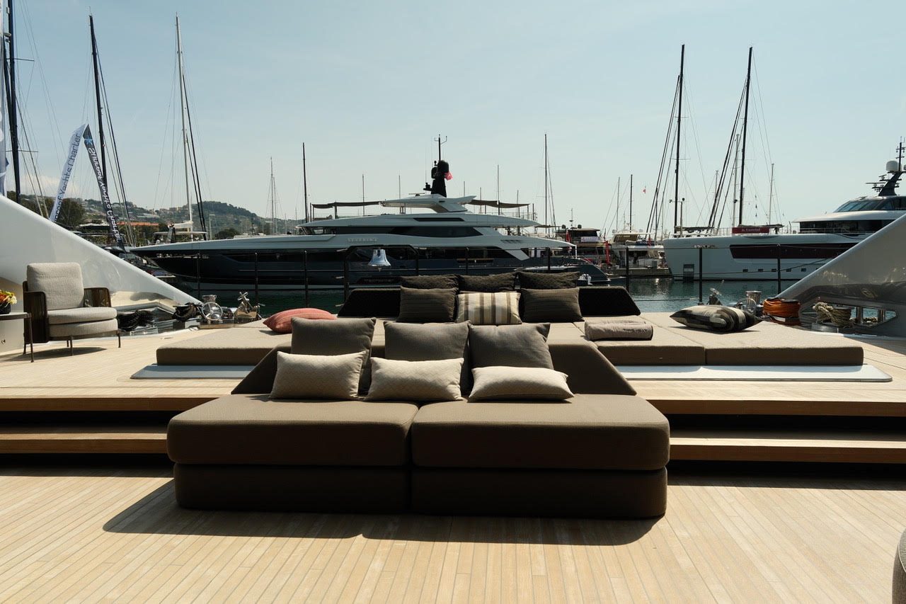 Spacious sofa on the deck of a superyacht, with a harbour full of yachts behind