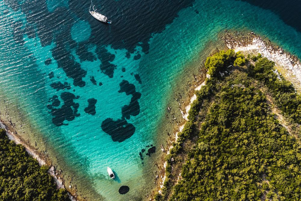 A turquoise bay in southern Dalmatia from above, with a sailing yacht and a motorboat