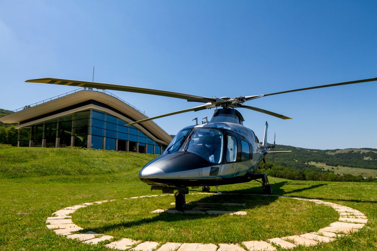 Modern helicopter on a landing pad in front of a glass building