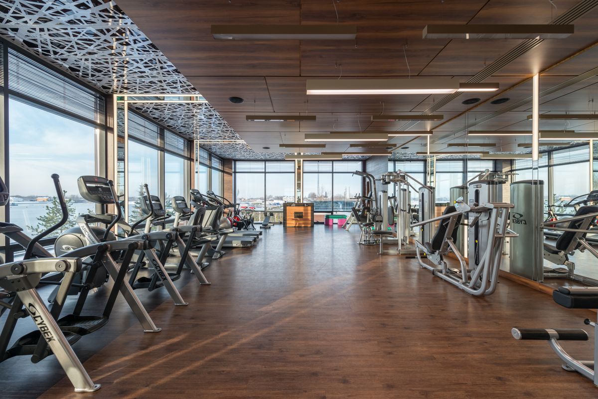 Treadmills and equipment in a bright gym with panoramic windows
